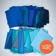 Array of small pieces of blue solid colored fabrics spread out randomly. 