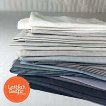 Array of small pieces of grey solid colored fabrics stacked.
